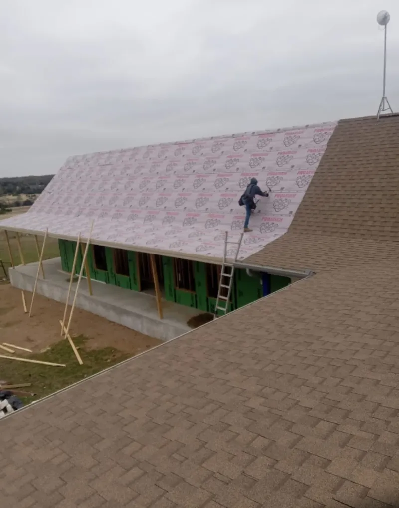 Worker preparing underlayment for a metal roof installation in Westwood Lakes